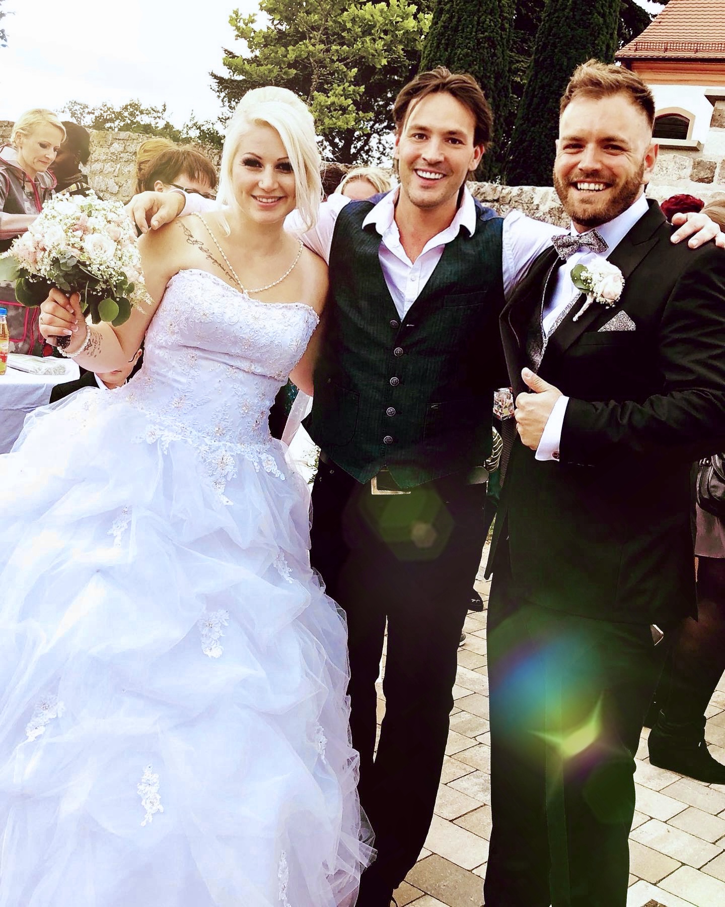 Sänger Rico Klemm posiert als herzlicher Gast Arm in Arm mit dem strahlenden Brautpaar für ein gemeinsames Erinnerungsfoto.