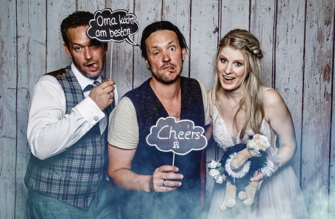 Spaß in der Fotobox: Sing-DJ Rico Klemm schneidet zusammen mit dem Brautpaar lustige Grimassen und sorgt mit witzigen Requisiten für unvergessliche Erinnerungsfotos.